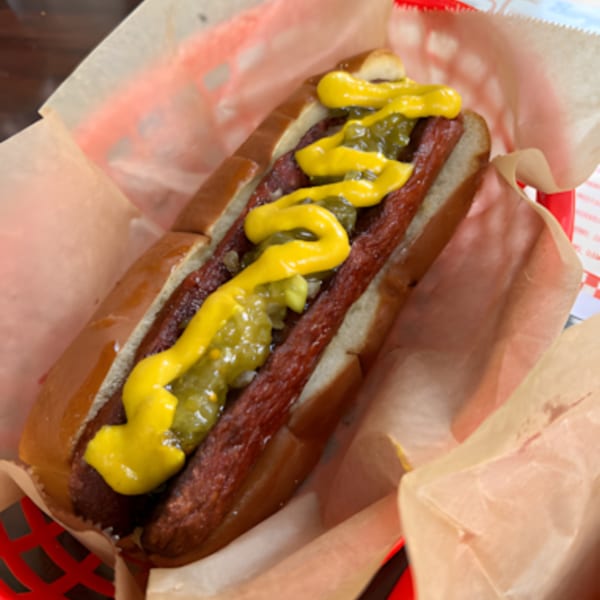 A Jordan's Hot Dog with mustard and relish in a red basket lined with paper.