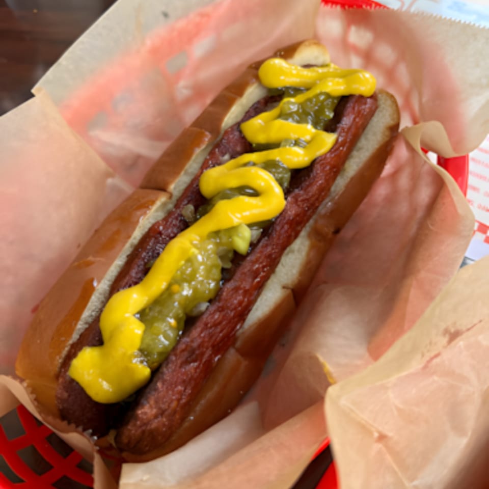 A Jordan's Hot Dog with mustard and relish in a red basket lined with paper.